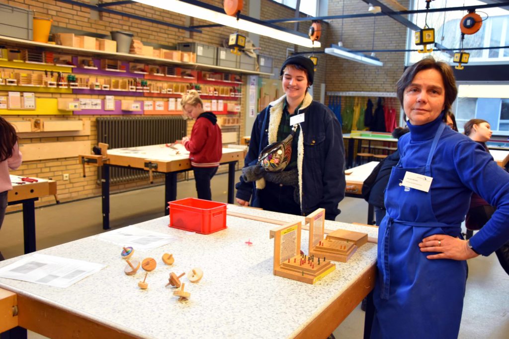 Mitarbeiterin in Arbeitskleidung und Kollege in der Werkstatt.
