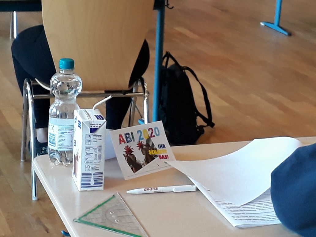Prüfungstisch mit Wasserflasche und Unterlagen.