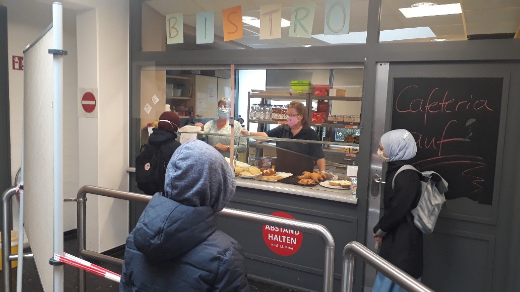 Schülerinnen und Schüler stehen an der Theke der Cafeteria an.