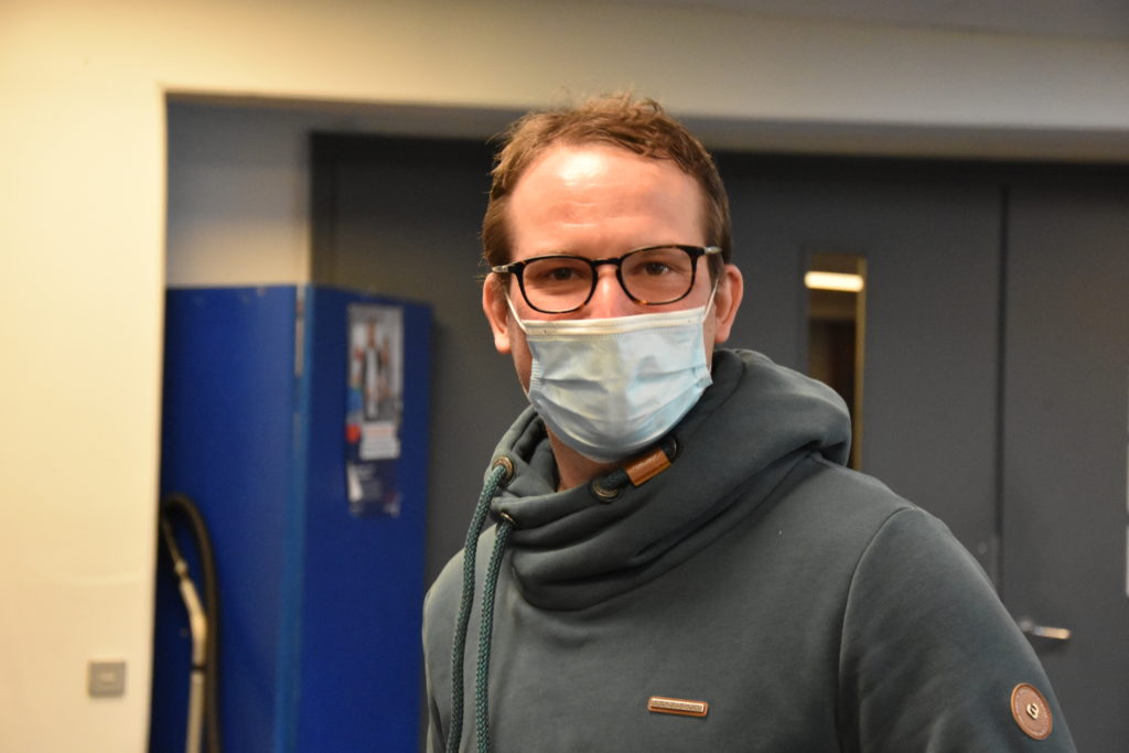 Kollege mit Brille und Maske im Flur.