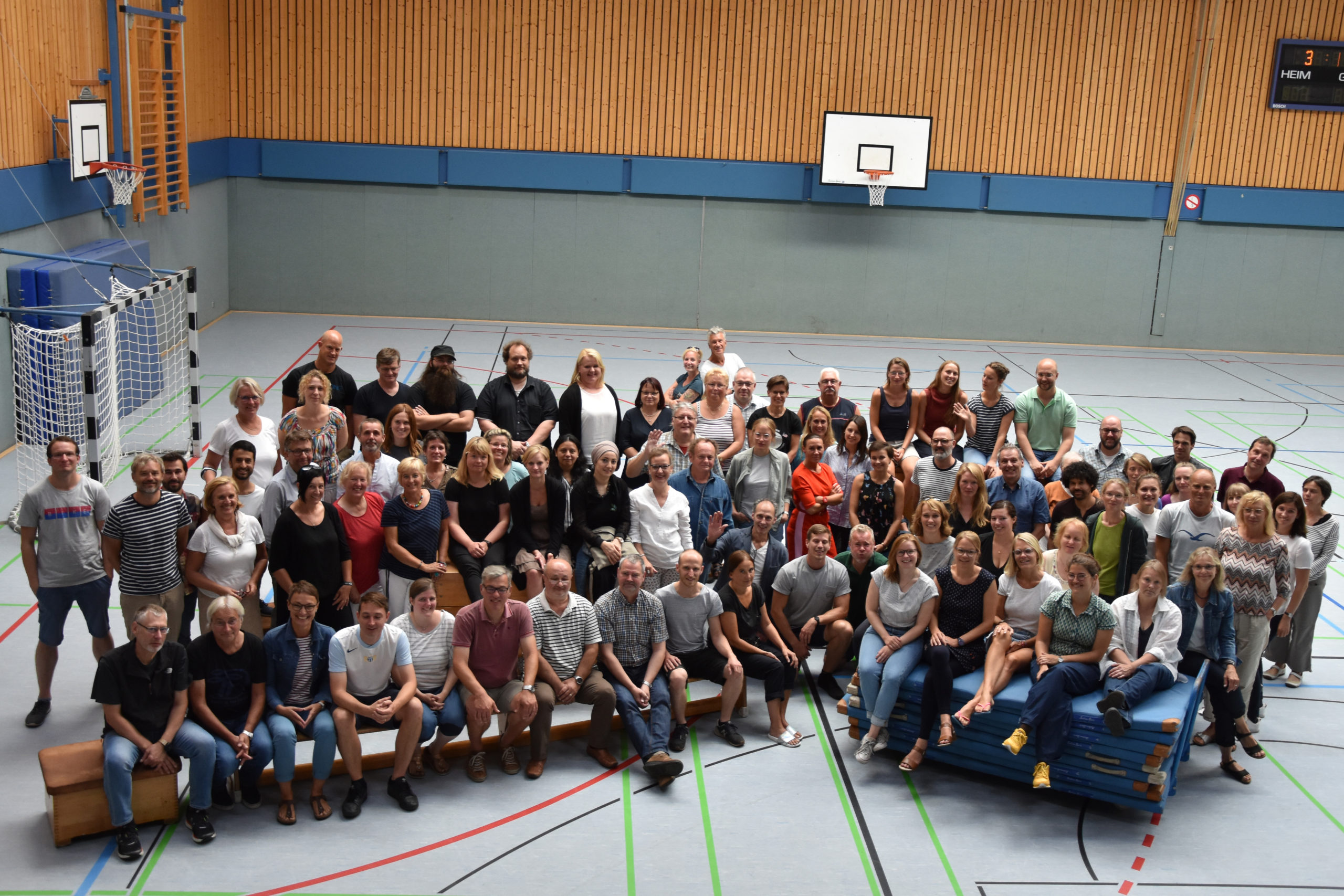 Großes Gruppenfoto der Mitarbeiterinnen und Mitarbeiter in der Sporthalle.