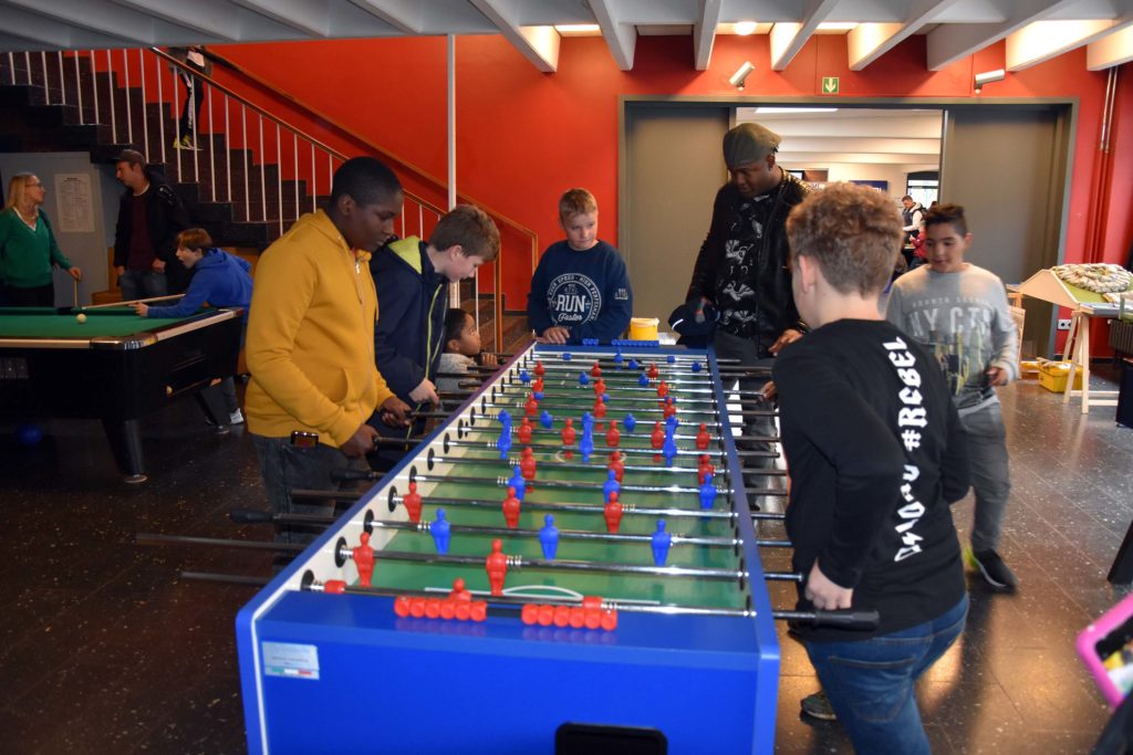 Schüler spielen im Pausencafé am Kickertisch.