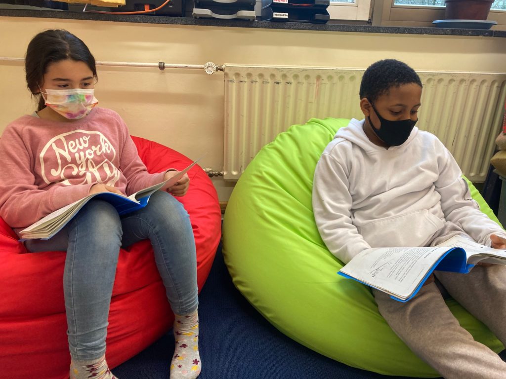Zwei Kinder lesen gemütlich auf Sitzsäcken.