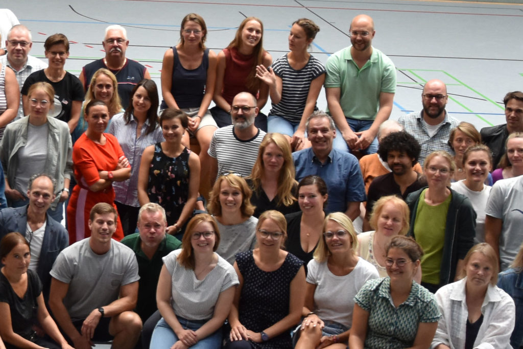 Großes Gruppenfoto des Kollegiums in der Sporthalle.
