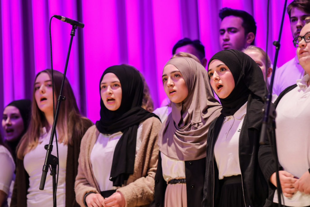 Sängerinnen des Schulchors beim Auftritt vor violettem Bühnenlicht.