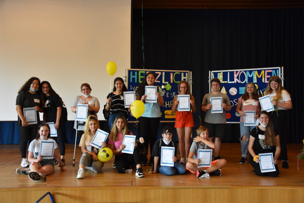 Prefects mit Urkunden und Ballons vor einem Willkommensbanner.