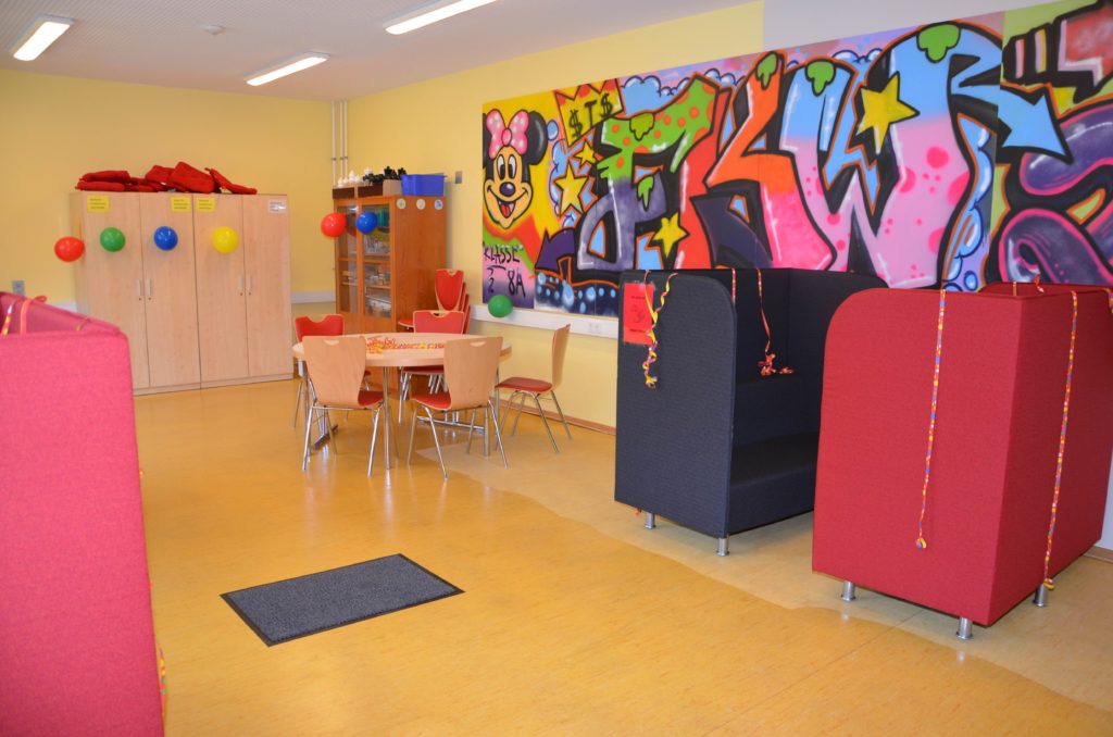 Pausenraum mit bunter Graffiti-Wand und Sitzmöbeln.