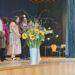 Begrüßung der neuen 5. Klassen auf der Bühne der Aula, vorne ein Strauß Sonnenblumen.