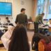 Schülerinnen und Schüler im Unterricht, vorne ein Bildschirm.