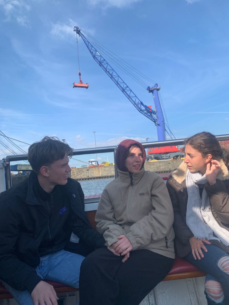 Jugendliche auf einem Boot im Hafen, im Hintergrund ein Kran.
