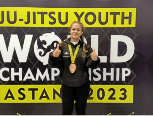 Jette Kuhn mit Medaille vor dem Banner der Ju-Jitsu Youth World Championship 2023 in Astana.