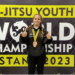 Jette Kuhn mit Medaille vor dem Banner der Ju-Jitsu Youth World Championship 2023 in Astana.
