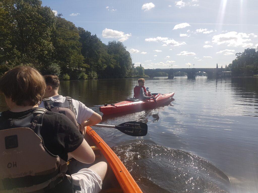 Blick aus einem Kanu auf die Alster, im Hintergrund weitere Boote.
