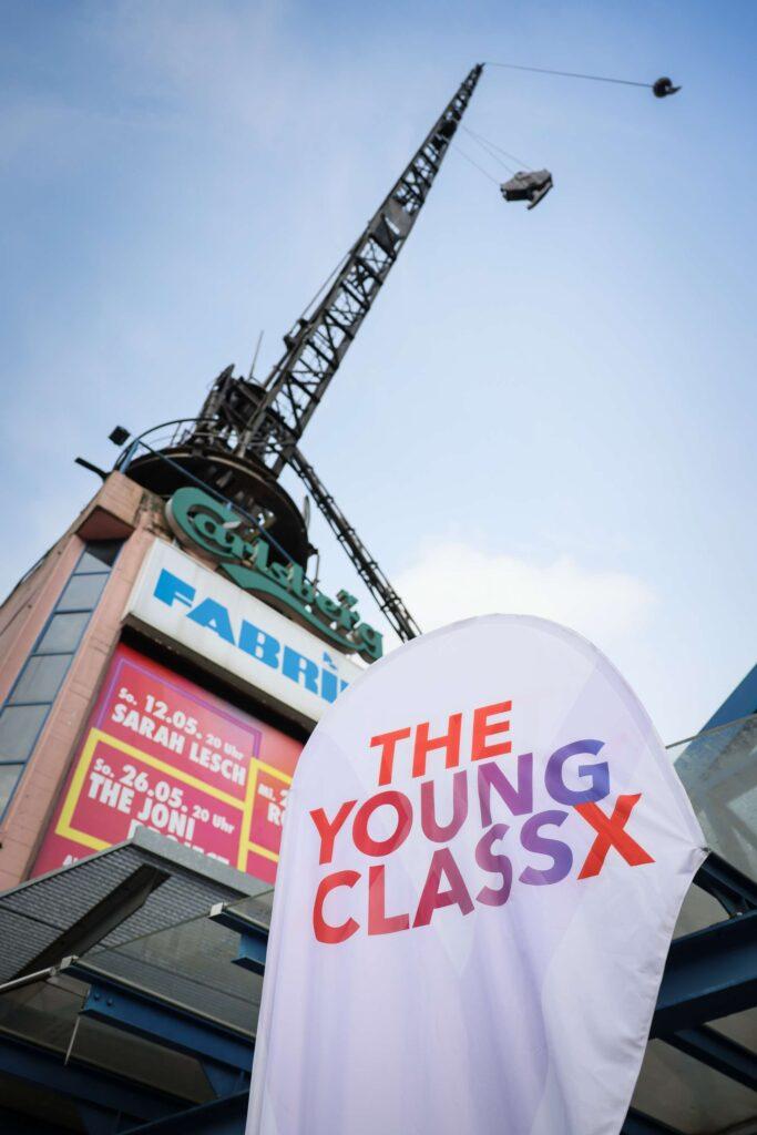 Beachflag mit dem Logo von The Young ClassX vor einem Kran.