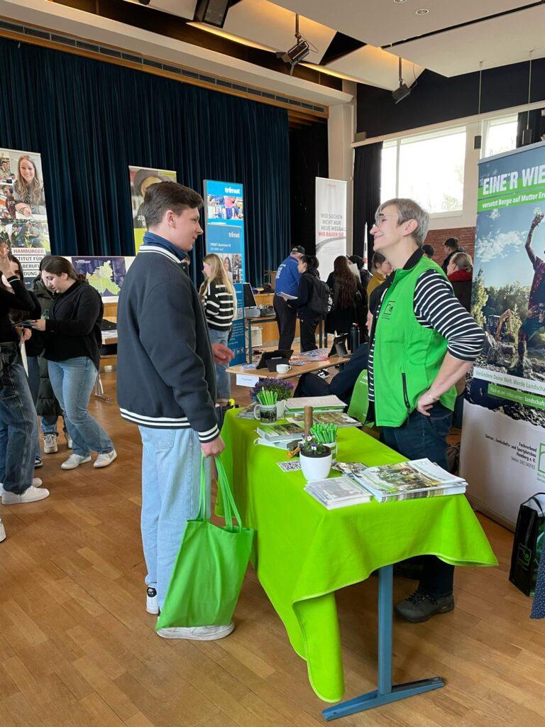Infostand mit grüner Tischdecke bei der Berufsmesse.