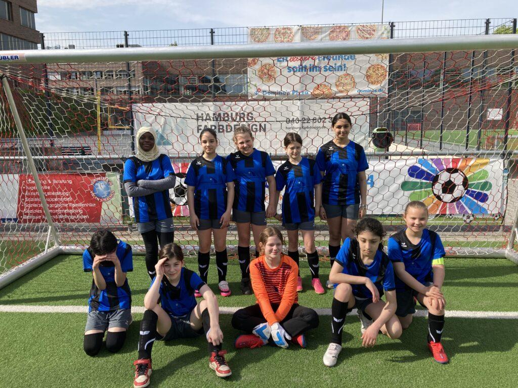 Fußballmannschaft der Schule auf einem Kunstrasenplatz.