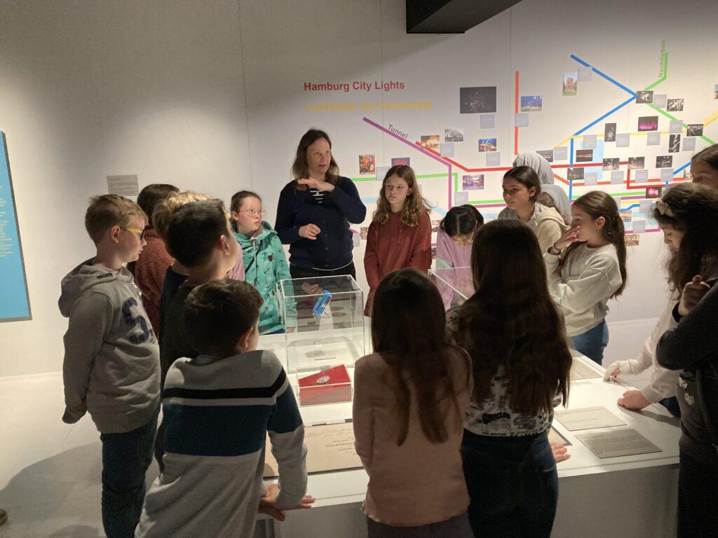 Klasse beim Besuch im Archäologischen Museum vor einer Ausstellungswand.