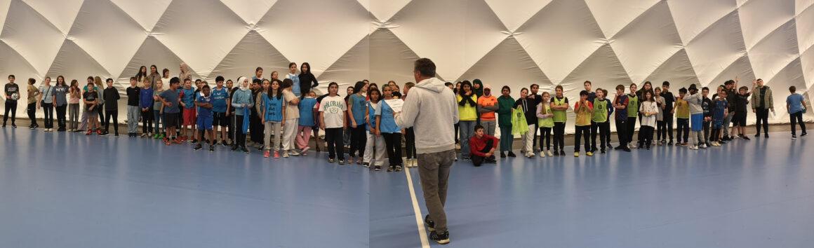 Viele Schülerinnen und Schüler stehen in einer langen Reihe in der Sporthalle.