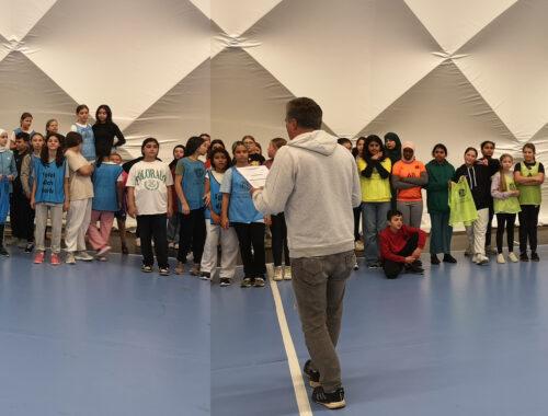 Viele Schülerinnen und Schüler stehen in einer langen Reihe in der Sporthalle.