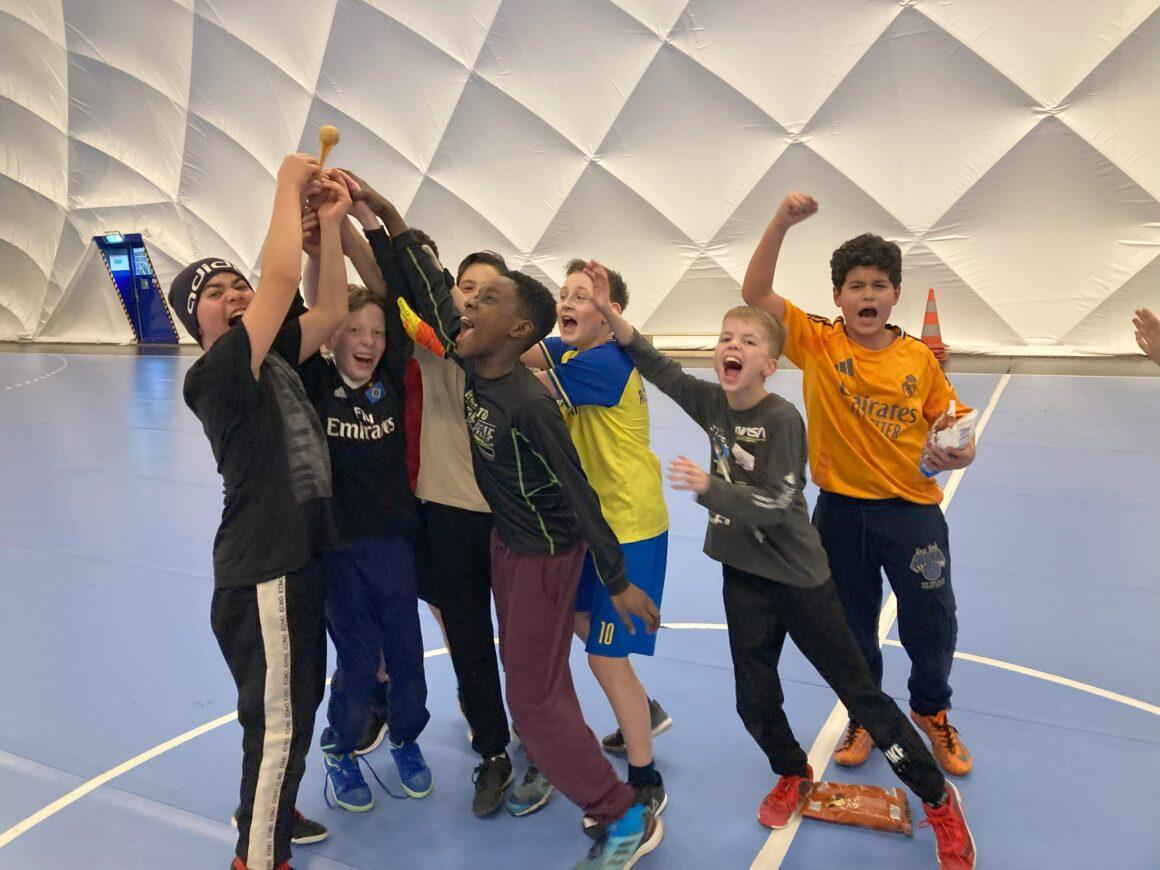 Schülerinnen und Schüler jubeln in einer Sporthalle.