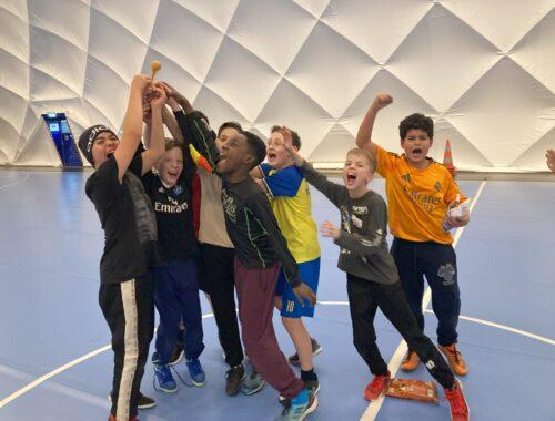 Schülerinnen und Schüler jubeln in einer Sporthalle.