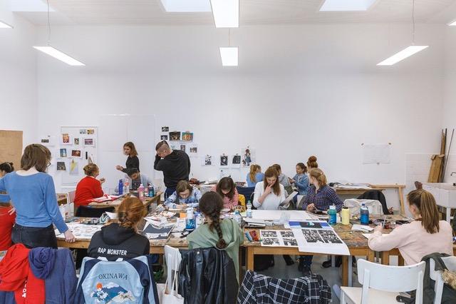 Jugendliche arbeiten im Kunstlabor an großen Tischen.
