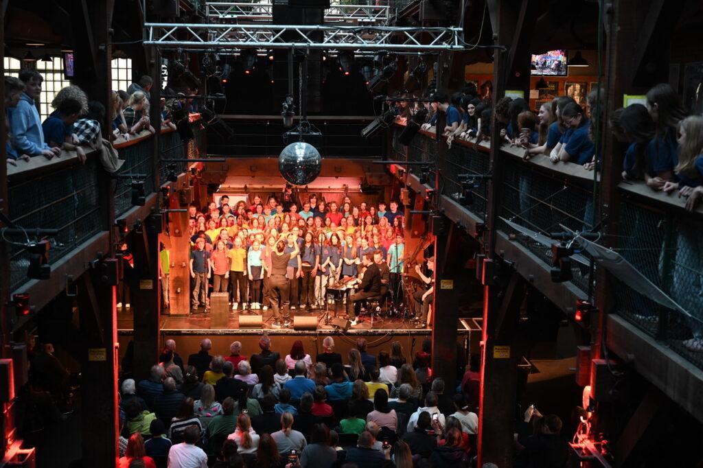Chor auf einer Bühne mit roter Beleuchtung beim Winterkonzert.
