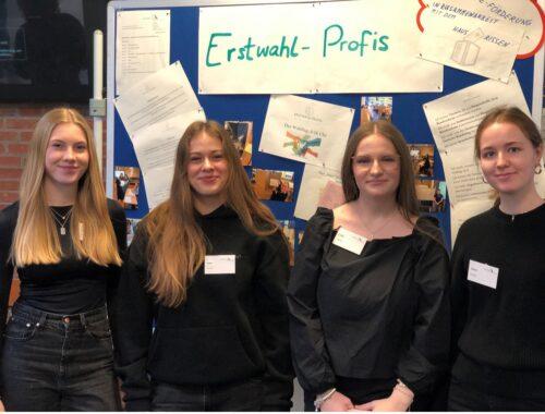 Vier Schülerinnen vor einer Pinnwand mit der Überschrift „Erstwahl-Profis“.