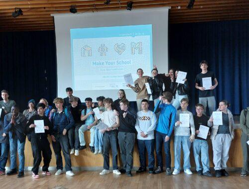 Gruppenfoto der Teilnehmenden der Hackdays auf der Bühne.