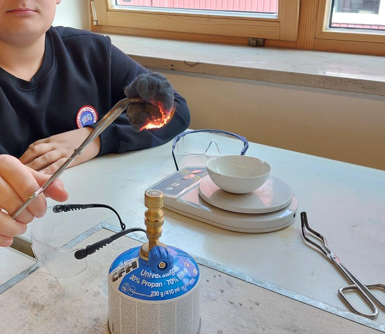 Schüler erhitzt im Chemieunterricht etwas mit dem Bunsenbrenner.