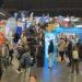 Jugendliche besuchen eine große Jobmesse mit vielen Ständen.