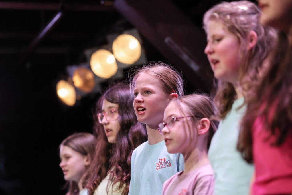 Kinder des Unterstufenchors singen auf der Bühne.