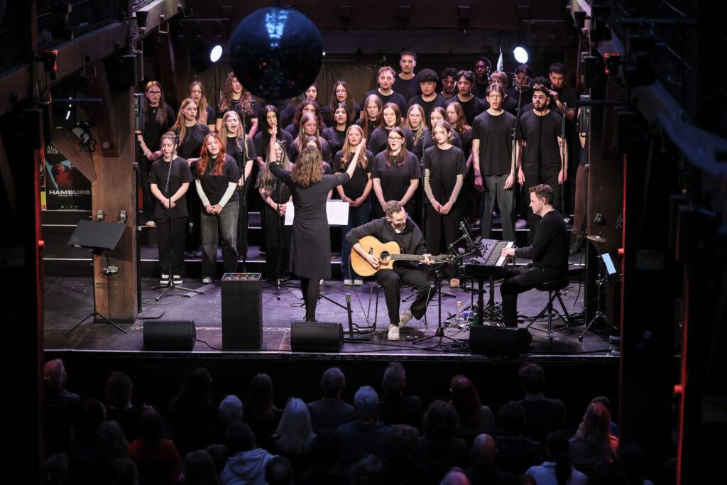 Chor in schwarzen T-Shirts auf der Bühne beim Stadtteilkonzert.