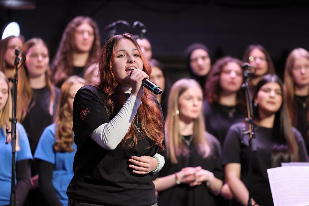 Sängerin am Mikrofon vor dem Chor beim Stadtteilkonzert.