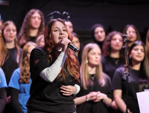 Sängerin am Mikrofon vor dem Chor beim Stadtteilkonzert.