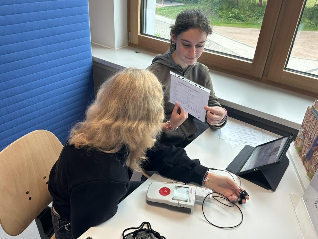 Schülerinnen bei einem Reaktionstest mit Tablet und Taster.